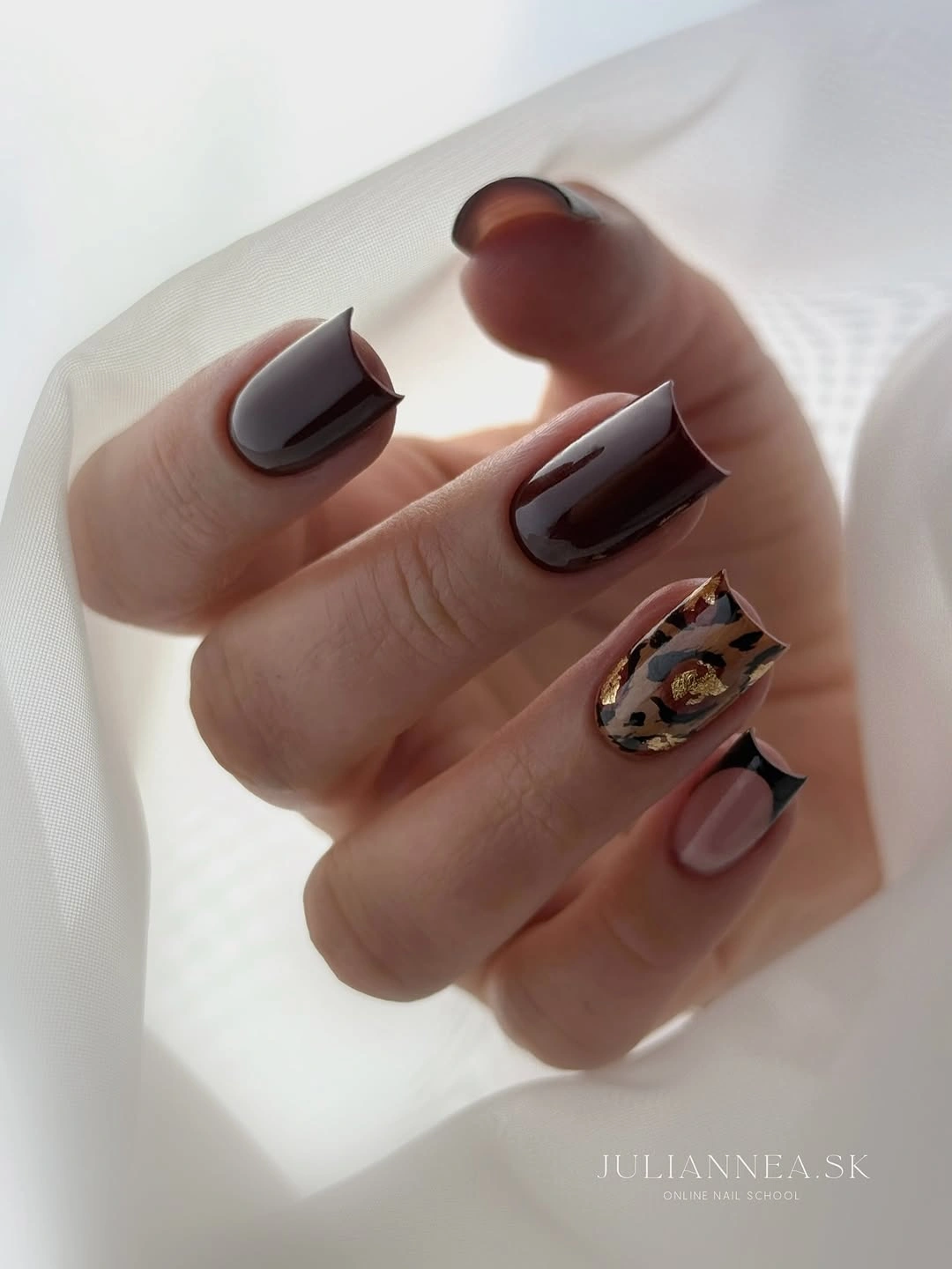 Dark square nails with animal-patterned accent and angular black French tip