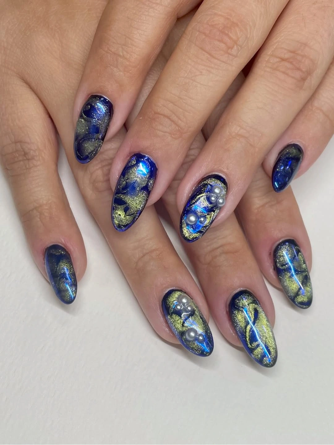 Almond nails with navy gold marbling, blue reflections and rounded accents