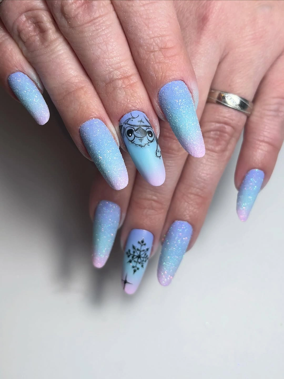 Long pastel blue and pink nails with cartoon character and snowflake illustrations