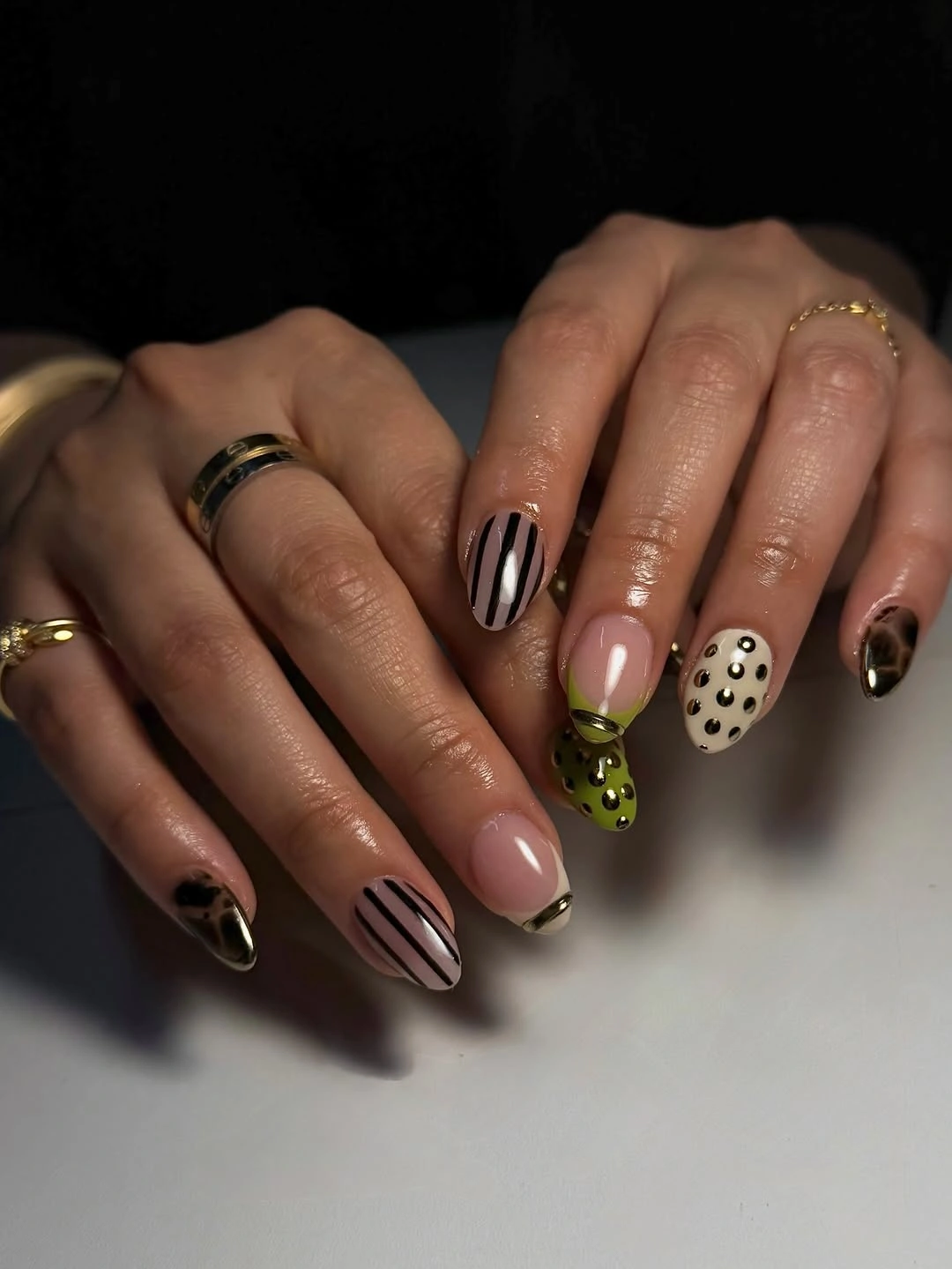 Almond nails with black stripes, spotted green tips and metallic-looking borders