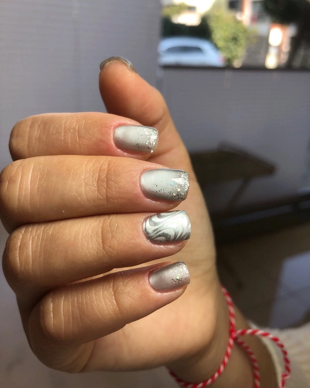 Short square silver-white nails with dark speckles and one gray swirl accent