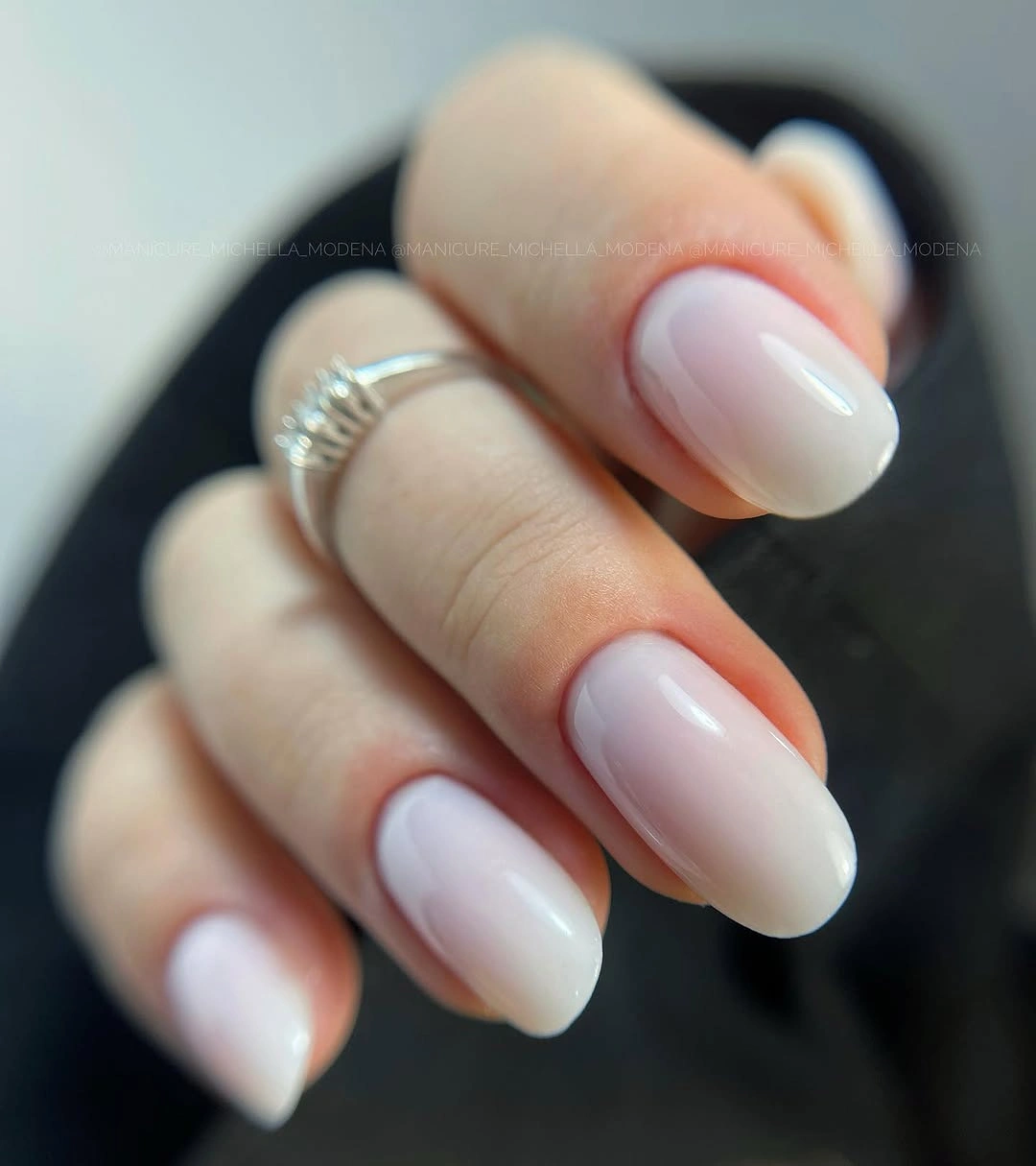 Short rounded nails in glossy milky white with faint pink gradients