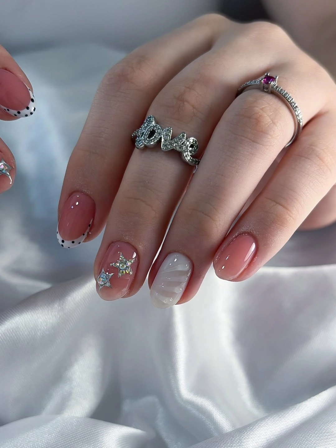 Short pink nails with black dotted French tips silver stars and white relief