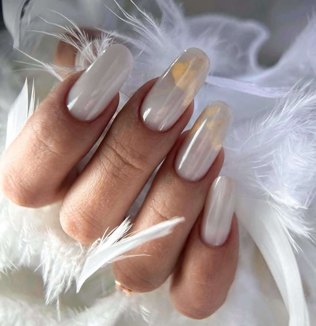 Long almond nails with glossy ivory color and diffuse cream patches
