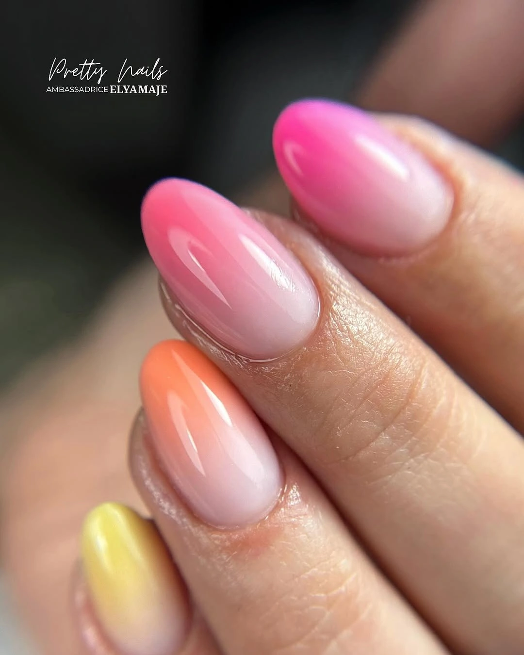 Almond nails with translucent pink bases and blended pink orange yellow tips