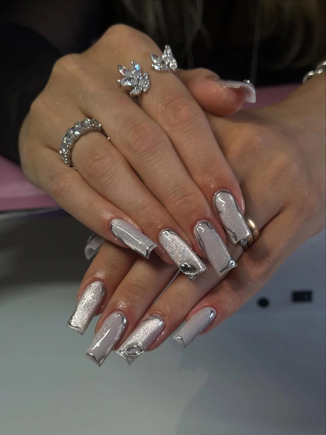 Long square nails with silver shimmer and reflective metallic outlines