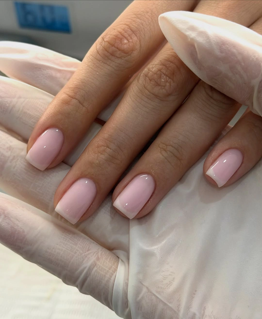 Short softly squared nails covered in pale glossy milky pink