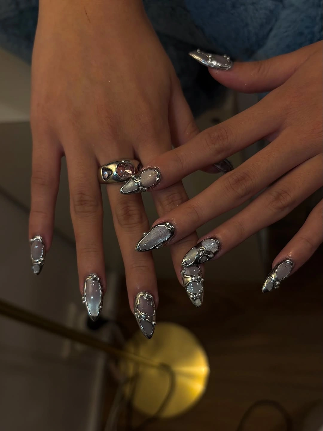 Long pointed nails with translucent gray centers and sculptural silver colored outlines